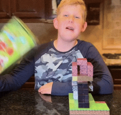Garçon construisant une structure inspirée de Minecraft avec les blocs magnétiques éducatifs Magnaft, sur une table de cuisine